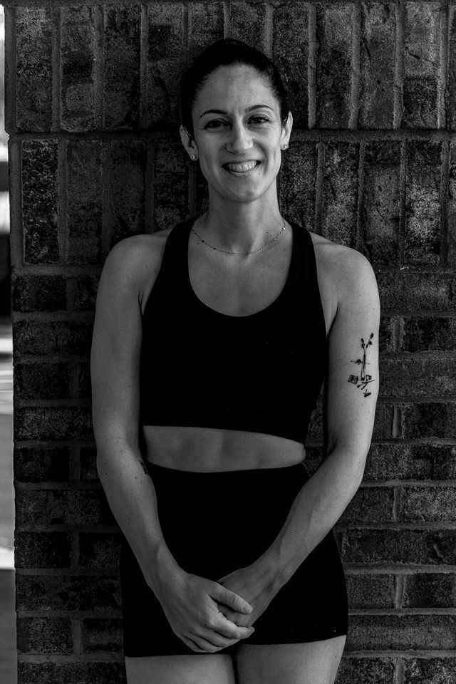 Studio founder smiling, standing against a brick wall