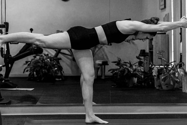 Practitioner balancing in warrior three with arms extended forward